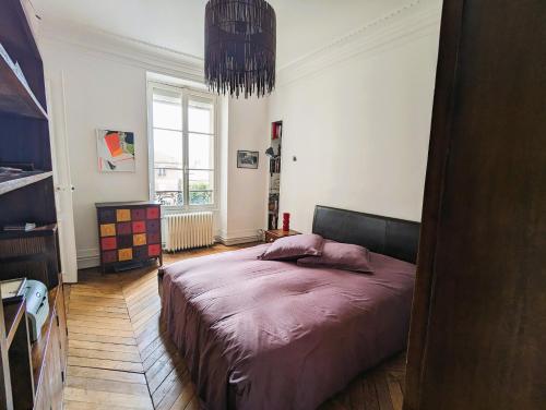 une chambre avec un lit et un lustre dans l'établissement Appartement typique et confortable - Voltaire, à Paris