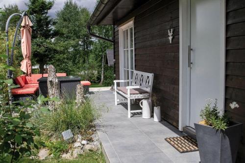 un porche de una casa con banco y sombrilla en Ferienhaus in Erlbach mit Grill und Terrasse, en Erlbach