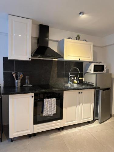 a kitchen with white cabinets and a black counter top at Studio Les Etoiles de Chasselay in Chasselay