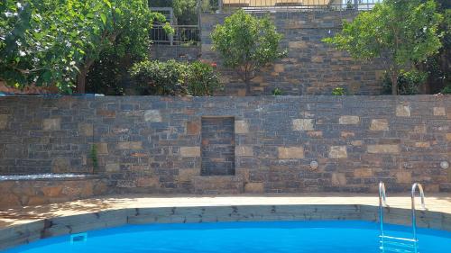 a brick wall next to a blue swimming pool at Beachfront Villa Phi φ in Agios Nikolaos