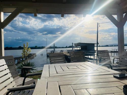 a dock with benches and the sun shining on the water at ElGringo Clisura Dunarii in Moldova Nouă