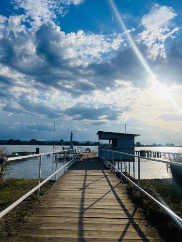 a wooden dock with a building on the water at ElGringo Clisura Dunarii in Moldova Nouă