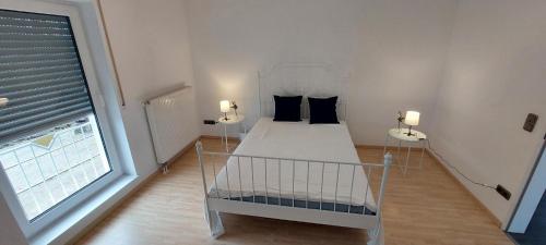 a bedroom with a white bed and a window at Gemütliche Ferienwohnung am Schwimmbad in Lengerich