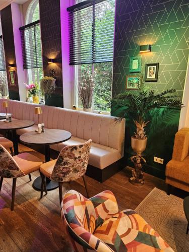 a restaurant with a couch and tables and chairs at Hotel De Villa in Dongen