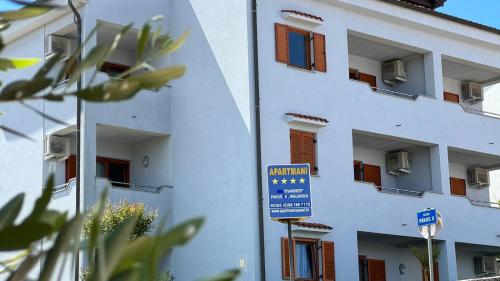 un bâtiment blanc avec un panneau bleu devant lui dans l'établissement Apartments Kvarner, à Malinska