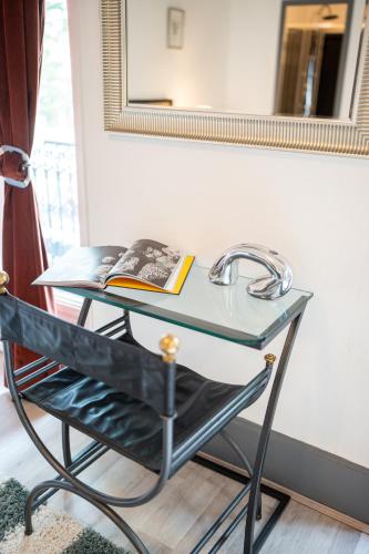 un bureau en verre avec un livre dessus à côté d'un miroir dans l'établissement Villa Vichéia - Appartement 13, à Vichy