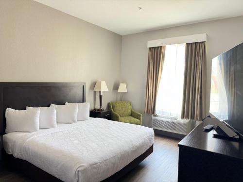 a hotel room with a bed and a chair and a desk at Sonesta Essential La Porte in La Porte