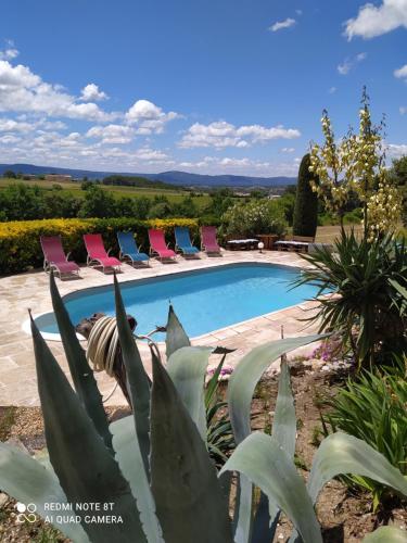 a pool with chairs and a plant in the foreground at La maison de Nazig in Pertuis