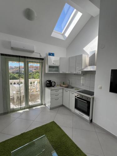 cocina con electrodomésticos blancos y ventana grande en Sunce apartments en Grebaštica