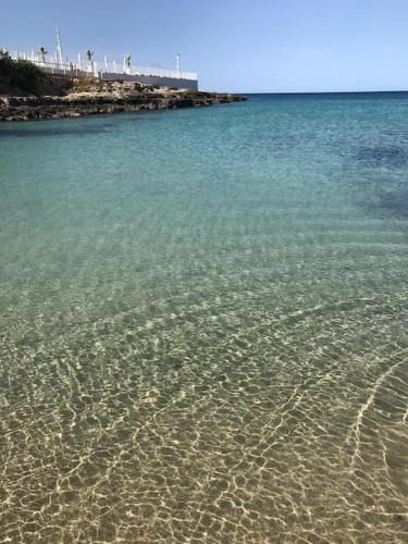 a beach with crystal clear water and footprints in the sand at La casa al mare in Ostuni Costa Merlata