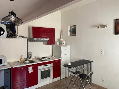 une petite cuisine avec des placards rouges et une petite table dans l'établissement Studio de la Croix avignon centre, à Avignon