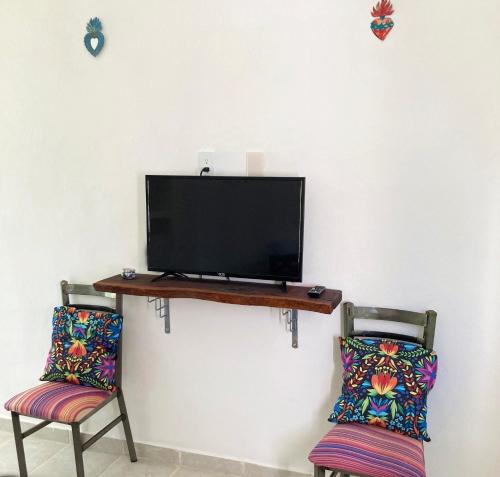 Dos sillas y un televisor en una pared con una mesa. en GREEN PARADISE LEONA VICARIO, en Leona Vicario