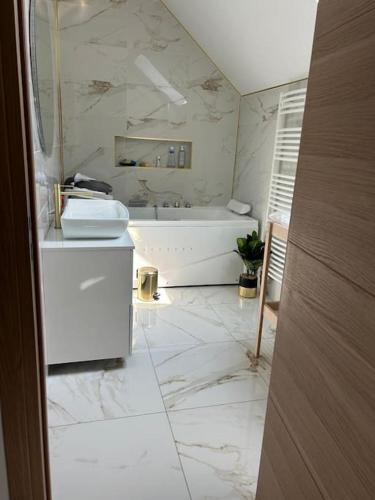 une salle de bain blanche avec une baignoire et un lavabo dans l'établissement belle maison avec piscine chauffée sans vis-à-vis, à Caudebec-lès-Elbeuf
