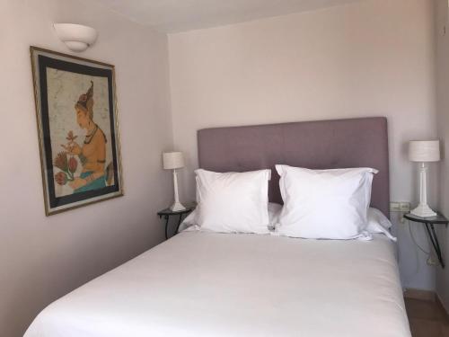 a white bed with two pillows and a painting on the wall at Boutique Hotel Mamabels in Mojácar