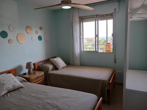 a bedroom with two beds and a window and a fan at Peñiscola Playa FRENTE AL MAR in Peniscola