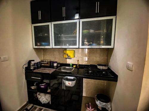 eine kleine Küche mit schwarzen Schränken und einem Herd in der Unterkunft Chalet Grand Hills North coast in Dawwār al Ḩajj Aḩmad