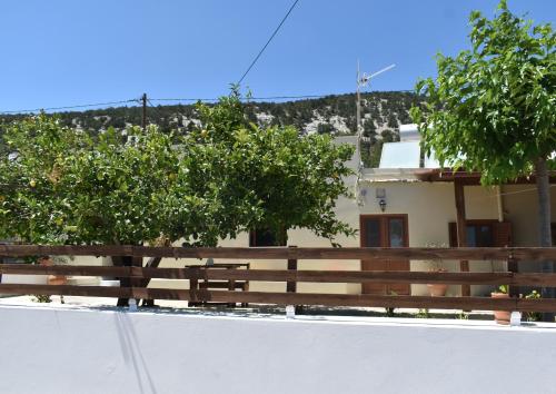 a fence and trees in front of a house at Lithos House in Monólithos