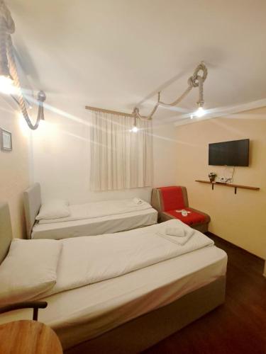 a room with three beds and a tv and a chair at Sebilhan Apart Hotel in Sarajevo