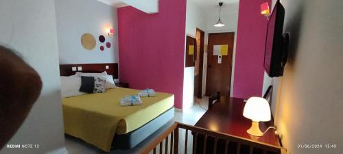 a bedroom with a bed with a pink wall at Hotel Alnacir in Faro