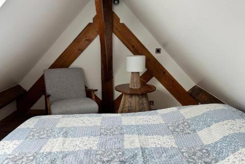 een slaapkamer op zolder met een bed en een stoel bij Tout à pied Dourdan Appartement in Dourdan