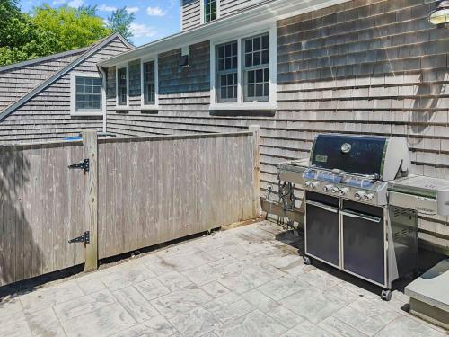 a backyard with a grill and a fence next to a house at 14 Hallet Lane Chatham Cape Cod - - Sand Simeon in Chatham