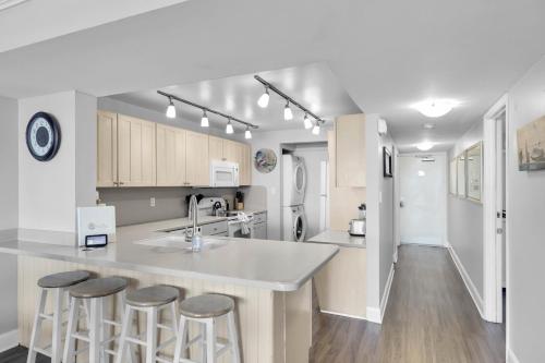 a kitchen with a counter and stools in it at Curacao - Large 2x2 Waterfront Condo Great View Pool & Dock in Key West