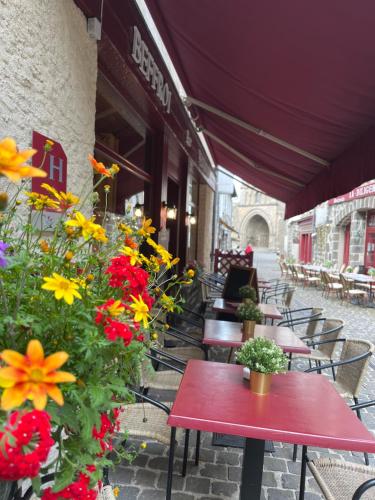 a group of tables with flowers on a patio at Hôtel Restaurant Le Beffroi in Salers