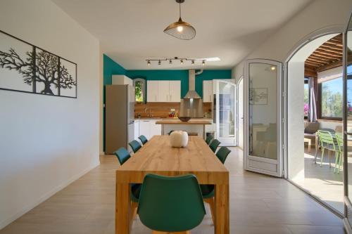 a dining room and kitchen with a wooden table and green chairs at 06Q - Biot beautiful provencal villa with swimming pool in Biot