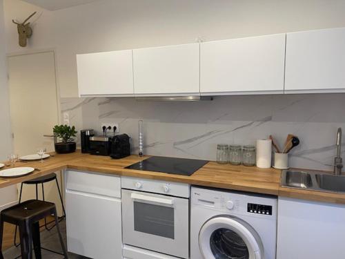 une cuisine avec des armoires blanches et une machine à laver dans l'établissement Appartement Centre ville, à Toulouse