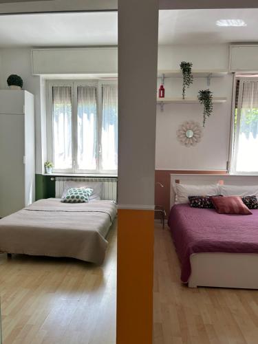 two beds in a room with two windows at Claudia's Home in FieraCity&MiCo&SanSiro in Milan