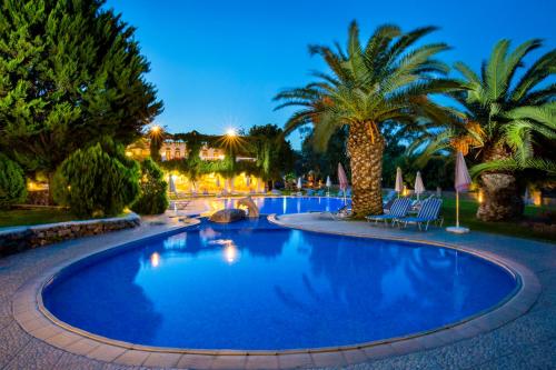 a large swimming pool with palm trees in a resort at Ekaterini Hotel in Kiotari