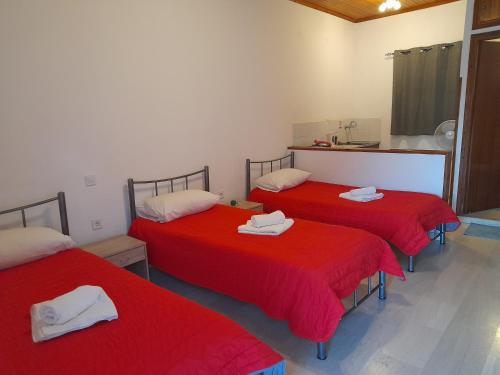 three beds in a room with red sheets at Sidari Studios in Sidari