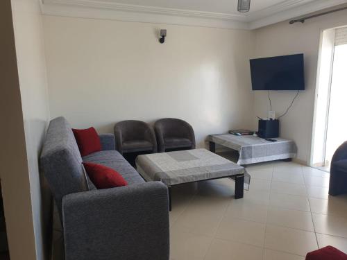 a living room with a couch and chairs and a tv at Assilah Marina Golf chez Ahmed in Asilah