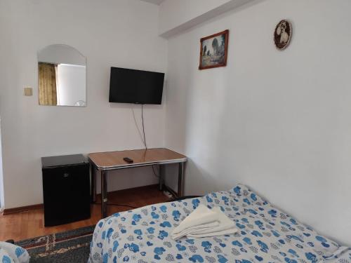 a bedroom with a bed and a table with a tv at Vila Didi, Mangalia in Mangalia