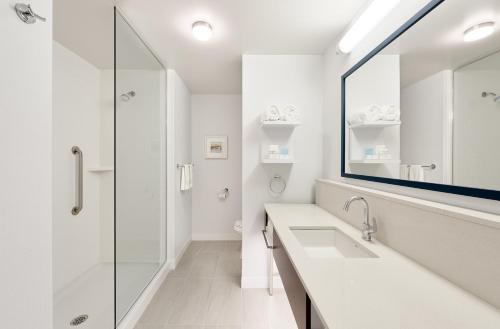 a white bathroom with a sink and a shower at Hampton Inn & Suites By Hilton Quebec City /Saint-Romuald in Lévis