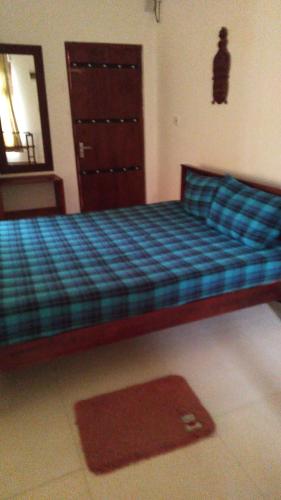 a bedroom with a bed with a blue plaid at Cottage 23 in Kurunegala