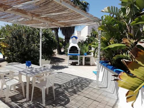 a patio with white tables and chairs and a grill at Sole&Mare in Monopoli