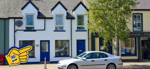 a white car parked in front of a building at Blue Door Apartment Main St, Carrigart, F92HC04 in Carrigart