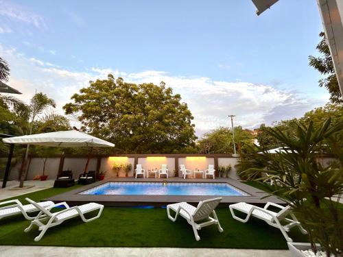 a swimming pool with lounge chairs and an umbrella at OCEAN DRIVE LODGE in Montañita
