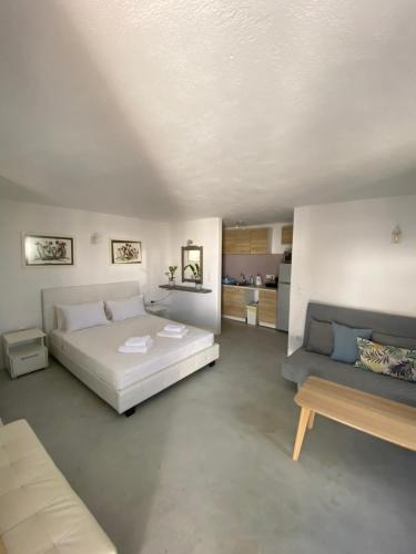 1 dormitorio con cama blanca y sofá en mykonos 1001 en Agios Stefanos