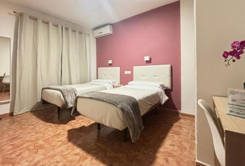 2 camas en una habitación de hospital con paredes púrpuras en Hostal Rocamar en Almuñécar