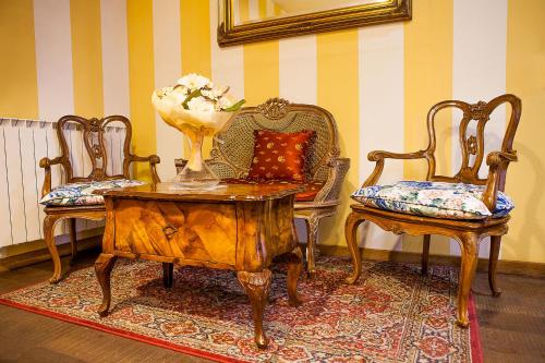 a living room with two chairs and a table with a vase of flowers at La Baita in Boario Terme