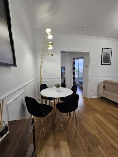 un salon avec une table et des chaises blanches dans l'établissement Appartement luxe - Colombes, à Colombes