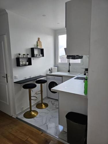 - une cuisine blanche avec deux tabourets de bar dans l'établissement Appartement luxe - Colombes, à Colombes