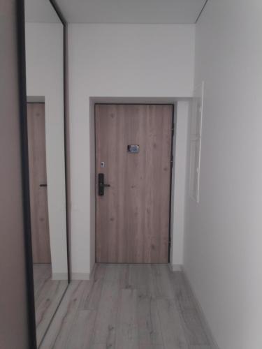 a hallway with a wooden door and a mirror at Aušros Alėjos Apartamentai in Šiauliai