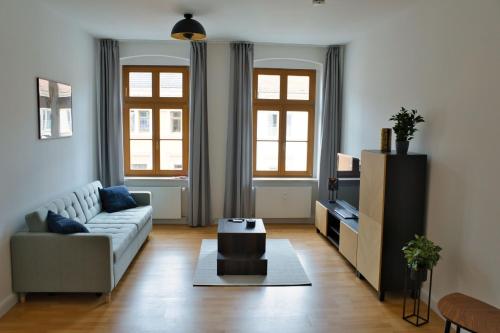 a living room with a couch and a tv at Sir Tobis Apartments - Sonnenhof - Zentrumsnah - Modern in Görlitz
