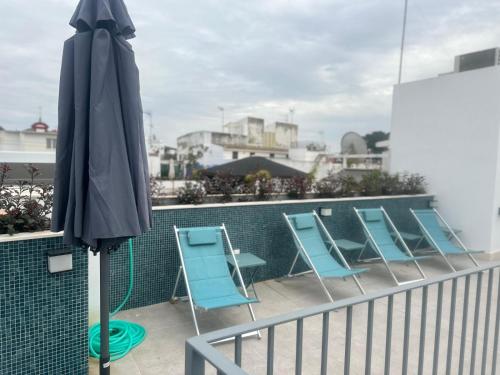 eine Reihe blauer Stühle und ein Sonnenschirm auf dem Balkon in der Unterkunft Posada de los Venerables in Sevilla