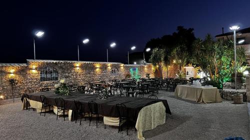 a set of tables and chairs in front of a stone wall at Villabosco in Favara