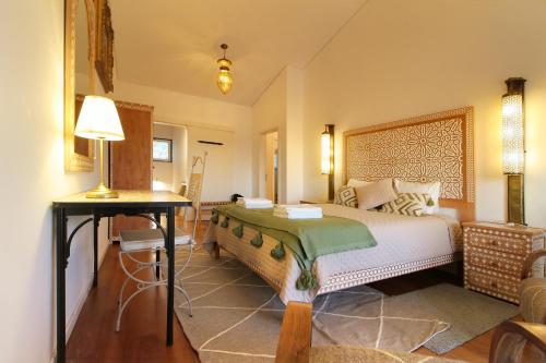 una camera da letto con un letto e un tavolo con una lampada di Fonte dos Pássaros a Vila Nova de Milfontes