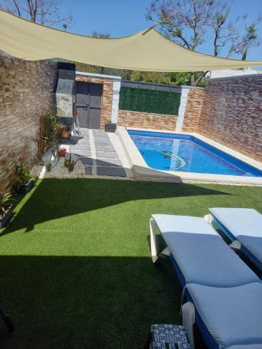 a backyard with a swimming pool and green grass at Casa Adosada in Bormujos